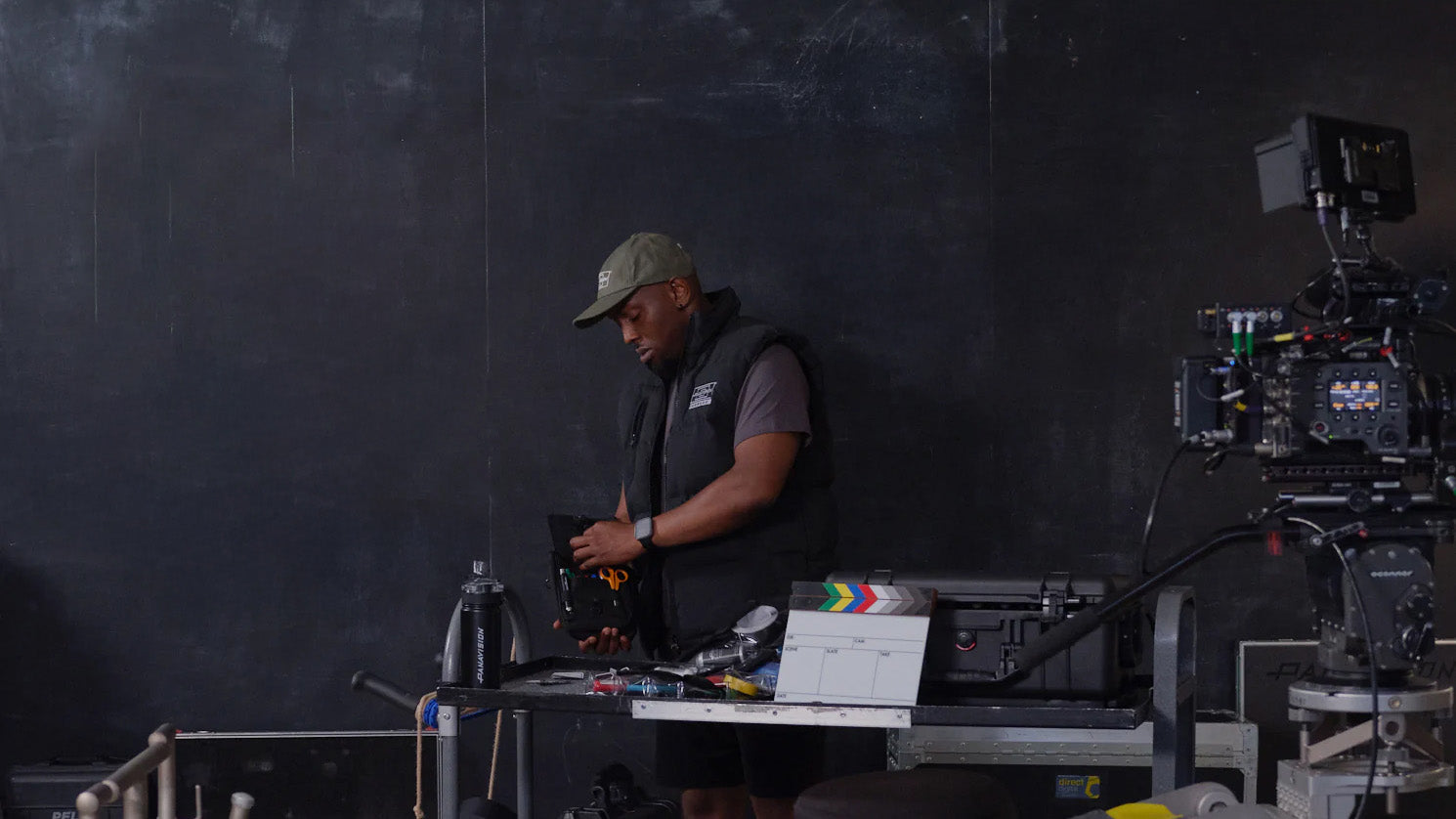 Person operating camera equipment on a film set with a dark background